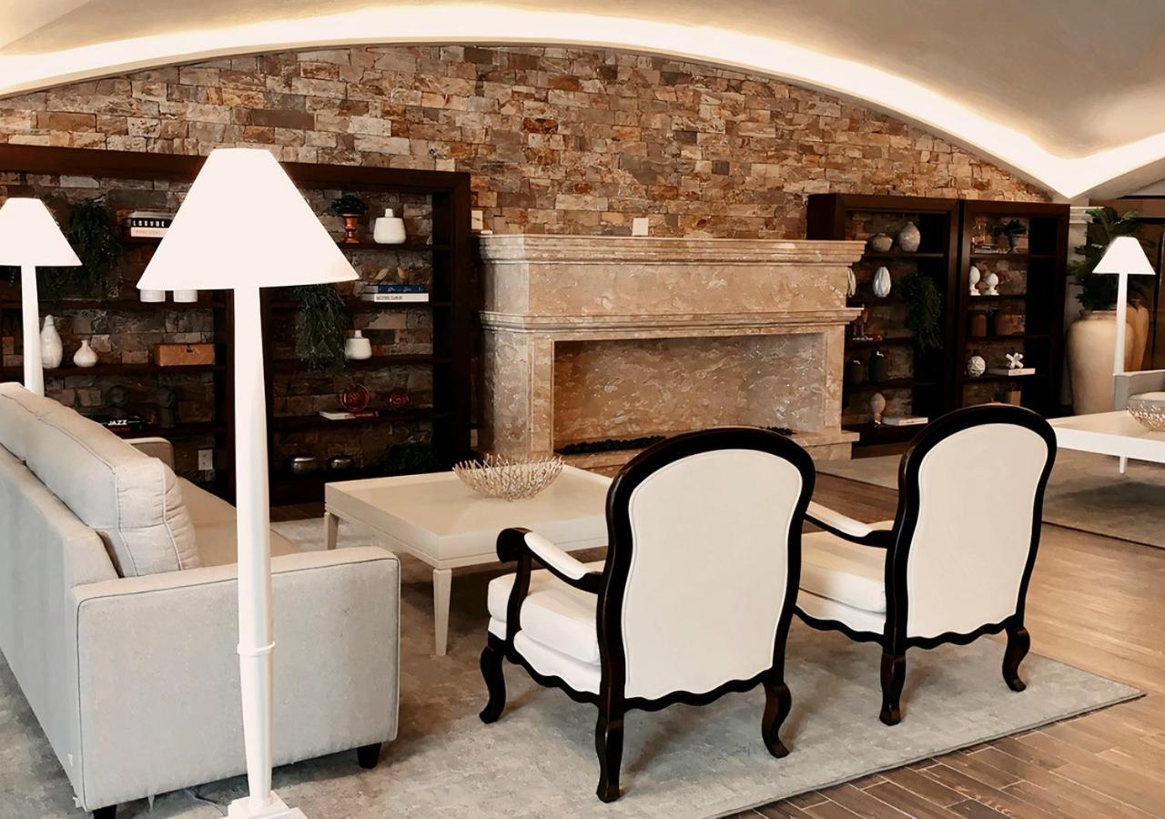 Buona Vitta Gramado Resort & Spa By Gramado Parks 외부 사진 The photo shows a stylish living room with a modern design. In the center, there is a light-colored sofa and two elegant white armchairs with black wooden frames. A coffee table is placed in front of the sofa. Behind them, there is a large, decorativ