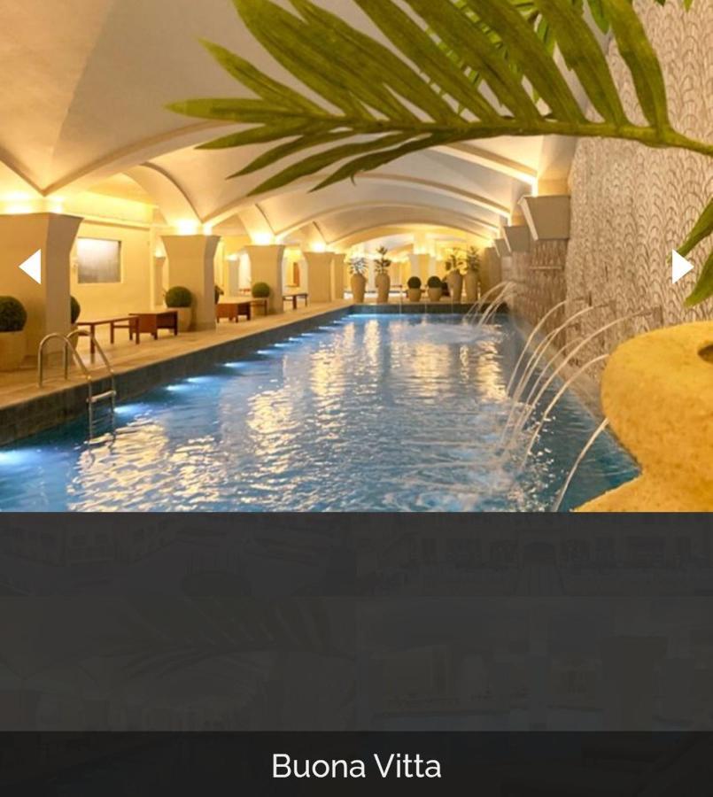 Buona Vitta Gramado Resort & Spa By Gramado Parks 외부 사진 The photo depicts an elegant indoor swimming pool area. The pool is illuminated with lights along its edge, and there are gentle water features creating a calming atmosphere. The ceiling has an arched design, and the space is decorated with plants an