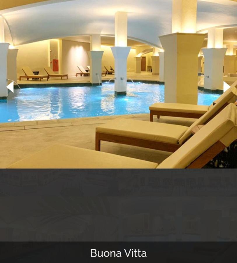 Buona Vitta Gramado Resort & Spa By Gramado Parks 외부 사진 The photo shows a tranquil indoor pool area, featuring a large swimming pool with clear blue water. Surrounding the pool are several lounge chairs made of light-colored wood, positioned for relaxation. The space is well-lit, with soft lighting highli