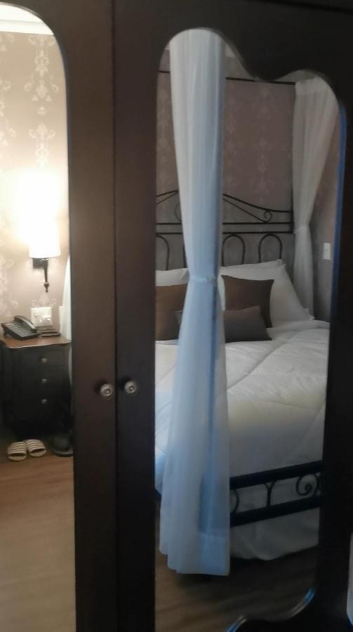 Buona Vitta Gramado Resort & Spa By Gramado Parks 외부 사진 The photo shows a cozy bedroom scene. It features a bed with white bedding and several brown accent pillows. The bed is framed by a decorative headboard and appears to be situated against a wall with subtle patterns. Next to the bed, there is a night