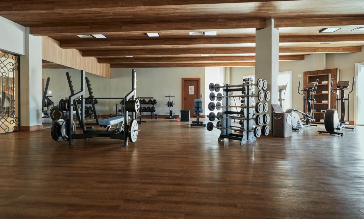 Buona Vitta Gramado Resort & Spa By Gramado Parks 외부 사진 The photo shows a spacious gym with a wooden floor and wooden ceiling beams. Various pieces of gym equipment are visible, including weight benches and racks with weights. On one side, there are free weights organized on a rack, while other equipment 