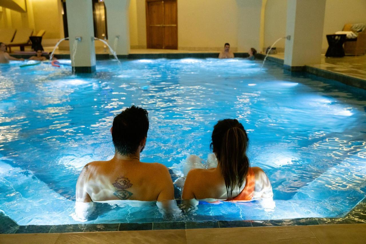 Buona Vitta Gramado Resort & Spa By Gramado Parks 외부 사진 The photo shows a couple sitting in a swimming pool with gentle lighting. They are facing away from the camera, appearing relaxed and enjoying their time together. The water is illuminated with a soft blue light, creating a serene atmosphere. In the 