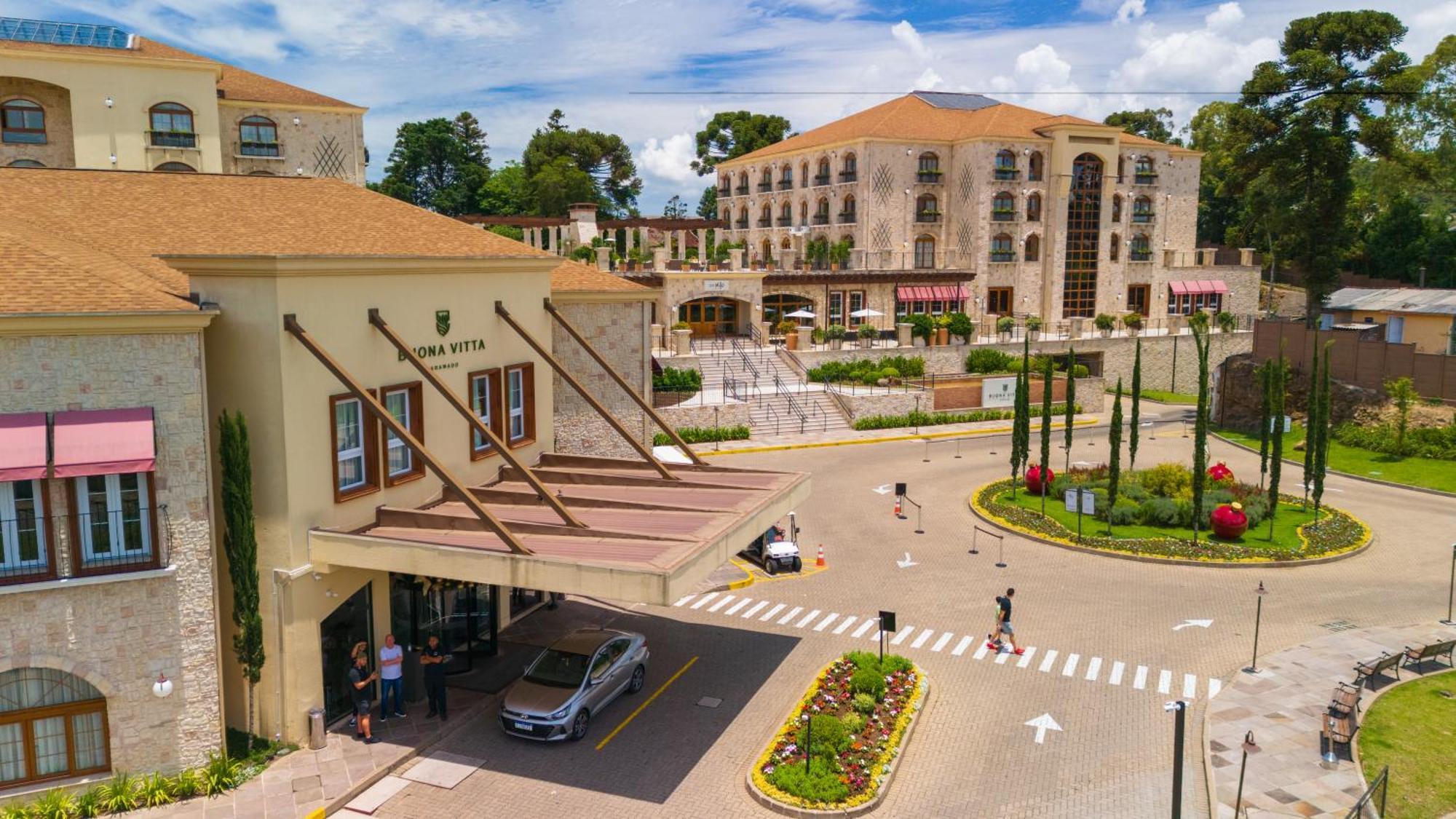 Buona Vitta Gramado Resort & Spa By Gramado Parks 외부 사진 The photo shows a luxurious hotel or resort entrance, featuring a modern yet elegant architectural design. In the foreground, there is a covered entrance where vehicles are likely dropping off guests. The building has a stone facade and a welcoming e